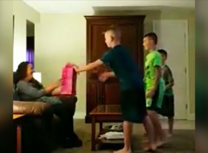 A három fiú letérdel apjuk barátnője elé és megkérik őt nyissa ki a csomagot