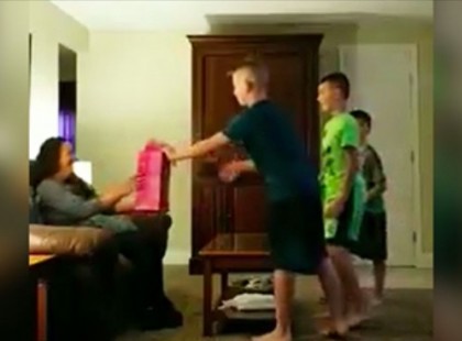 A három fiú letérdel apjuk barátnője elé és megkérik őt nyissa ki a csomagot